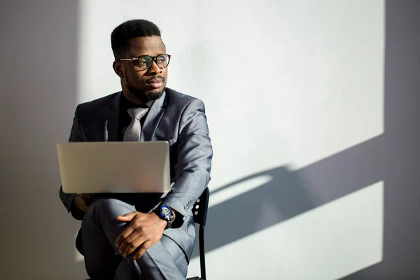 Colega de trabalho africano usando óculos e usando laptop no escritório — Fotografia de Stock