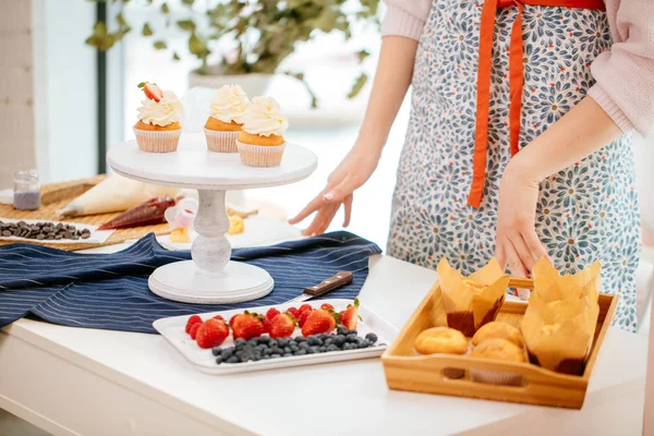 Panadero femenino decorando cupcakes con bayas — Foto de Stock