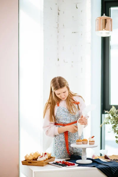 Mujer bastante joven decorando cupcakes en su cocina —  Fotos de Stock