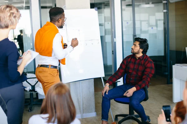 Afrikanischer Büroleiter zeigt seinem Chef Flipchart auf Flipchart — Stockfoto