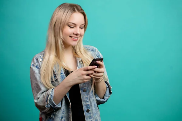 Χαρούμενη νεαρή καυκάσια γυναίκα χρησιμοποιώντας smartphone στο μπλε — Φωτογραφία Αρχείου
