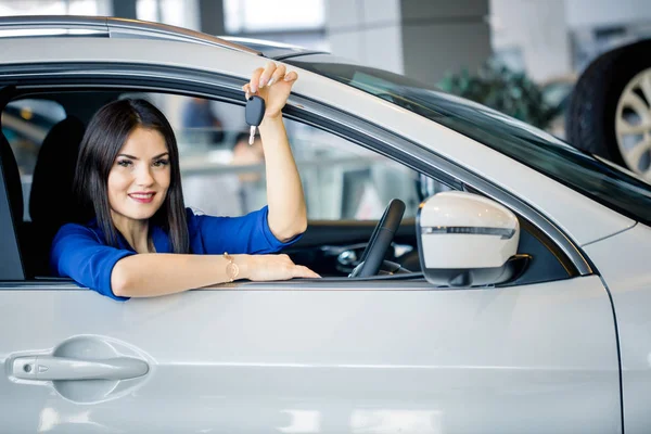 Frau mit Autoschlüssel sitzt in Neuwagen — Stockfoto