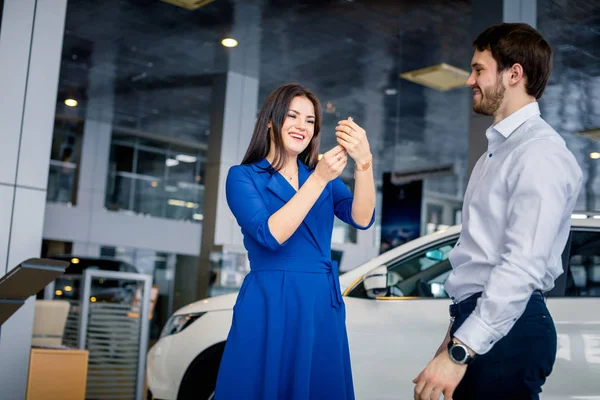 車のショールームで新しい車からキーを受け取る幸せな美しい女性 — ストック写真