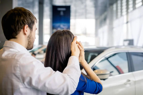 젊은 남자가 차 앞에 서 있는 여자 친구의 눈을 가리고 있습니다 — 스톡 사진