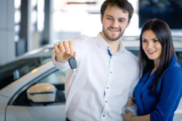 魅力的なカップルの所有者に新しい車の鍵を与える車の販売の女の子. — ストック写真