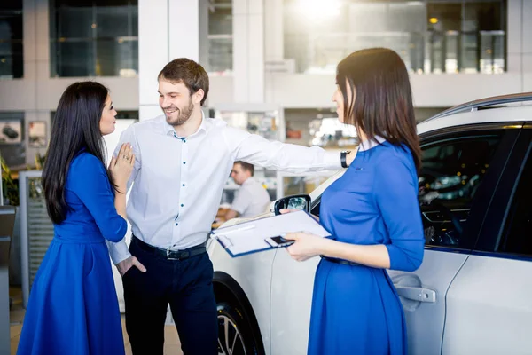 Young married couple buying their first car together in auto salon