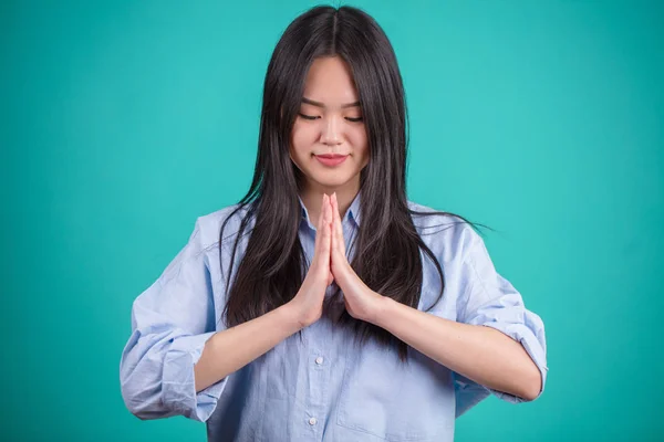 Азіатські молодій жінці молитися на тлі синього студії. — стокове фото