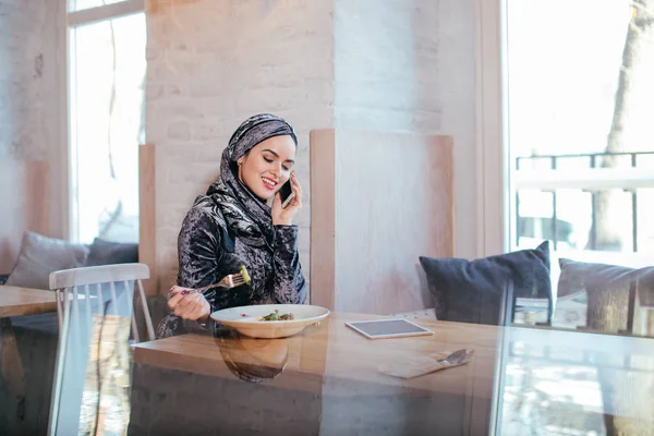 Jovem muçulmano mulher falando no telefone no café e olhando na janela — Fotografia de Stock