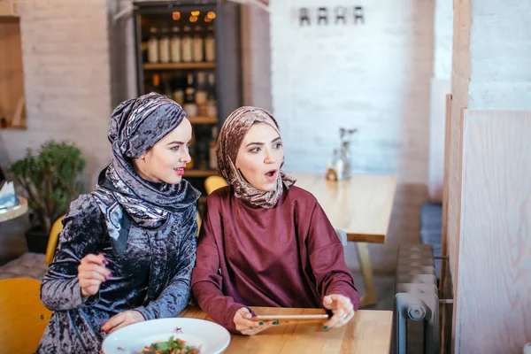 Dos mujeres musulmanas en la cafetería, comprar en línea usando tableta electrónica — Foto de Stock