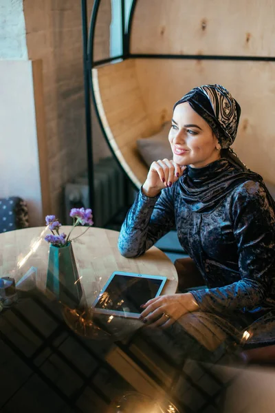 Красивая арабская мусульманка с помощью планшета в кафе — стоковое фото