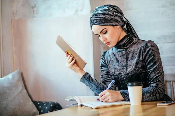 Мусульманские женщины, работающие с планшетами и пьющие кофе в кафе — стоковое фото