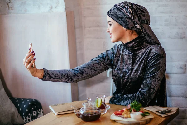 Mujer musulmana tomando selfie en la cafetería con smartphone — Foto de Stock