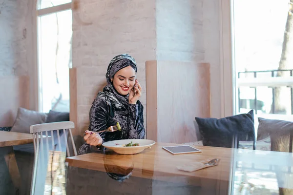 Jovem muçulmano mulher falando no telefone no café e olhando na janela — Fotografia de Stock