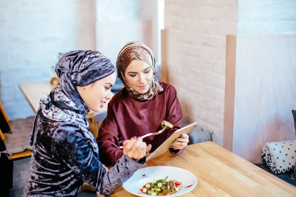 Deux femmes musulmanes dans un café, magasiner en ligne en utilisant une tablette électronique — Photo