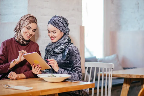 Dos mujeres musulmanas en la cafetería, comprar en línea usando tableta electrónica — Foto de Stock