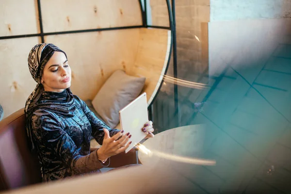 Красивая арабская мусульманка с помощью планшета в кафе — стоковое фото