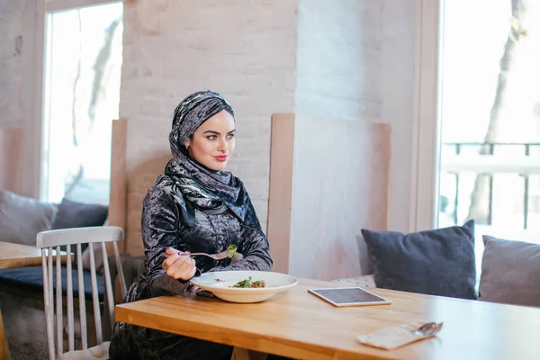 Мусульманская женщина ест в кафе с едой — стоковое фото