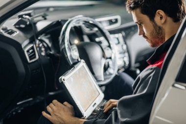 Mekanik, dizüstü bilgisayarın yardımıyla araba motorunu inceliyor
