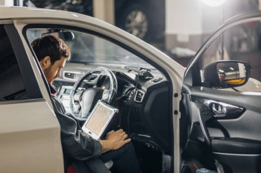 Mekanik, dizüstü bilgisayarın yardımıyla araba motorunu inceliyor