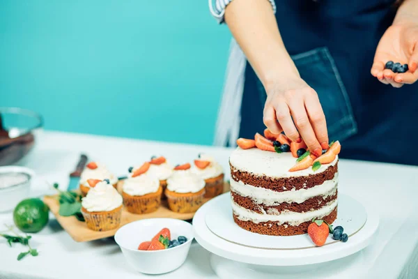 Imagen recortada de manos de mujer decorando cupcakes con bayas —  Fotos de Stock