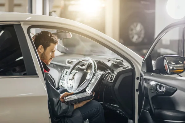 Mecánico examinar el motor del coche con la ayuda de la computadora portátil — Foto de Stock