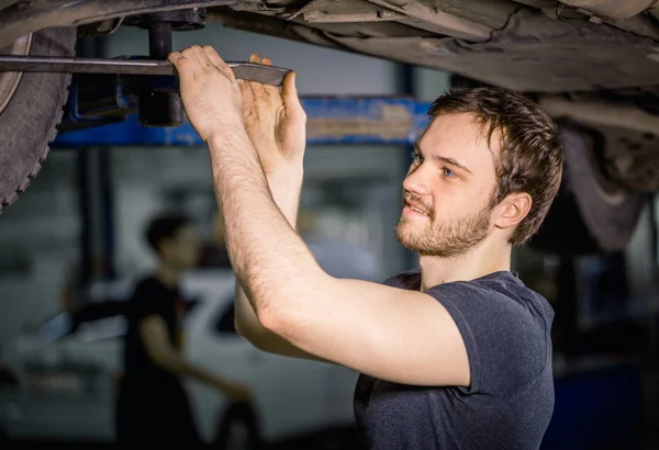 Механик под машиной в гараже: шиномонтаж и техническое состояние — стоковое фото