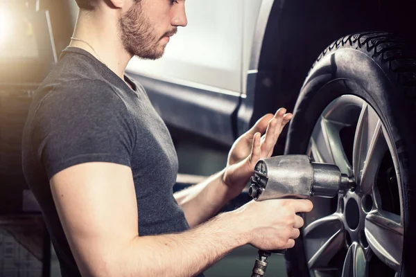 Mecánico cambio de rueda de coche en garaje de reparación de automóviles — Foto de Stock