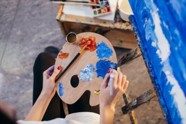 Petrol renk paletinde elinde tutan karıştırma kadın sanatçı