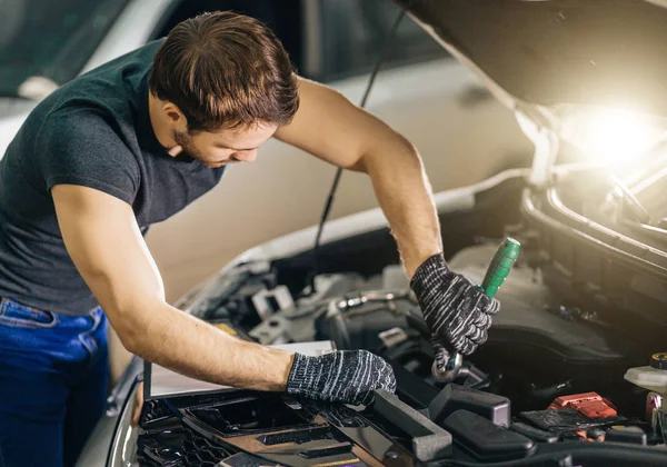 Monteur werkt onder motorkap van de auto in de garage voor reparatie — Stockfoto