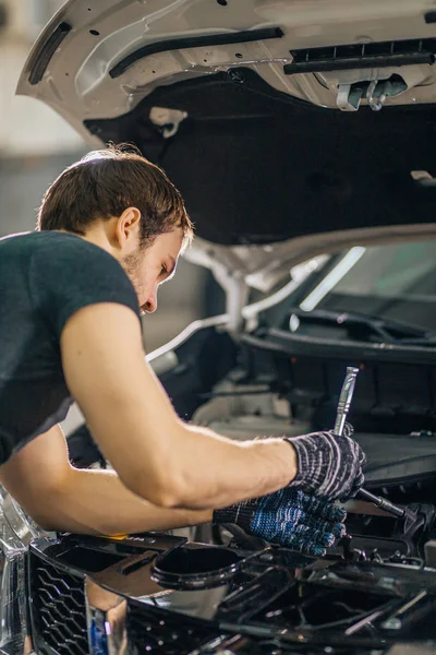Mecânico trabalhando sob o capô do carro na garagem de reparação — Fotografia de Stock