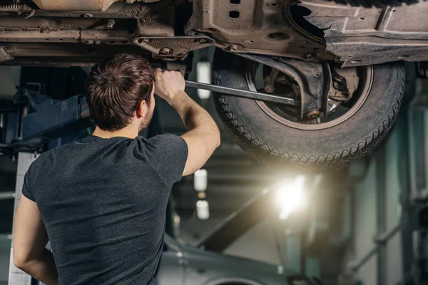 Mechanic onder auto in garage examen band en technische staat — Stockfoto