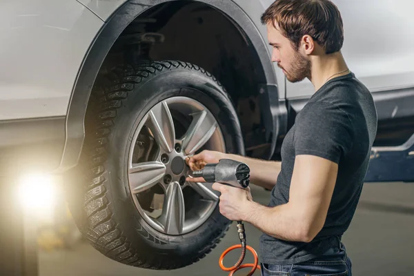 Meccanico che cambia ruota dell'automobile nel garage di riparazione auto — Foto Stock