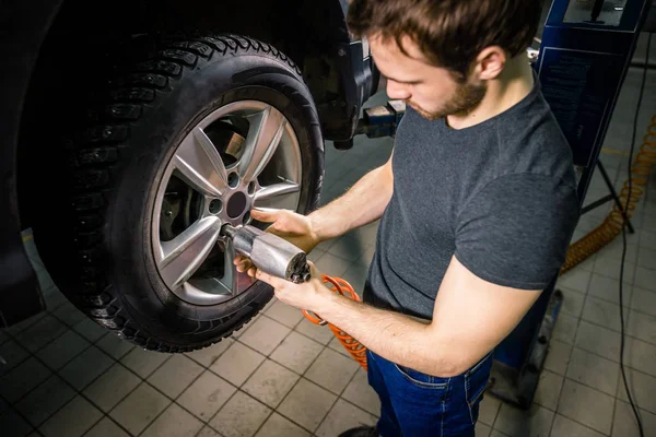 Mécanicien changer de roue de voiture dans le garage de réparation automobile — Photo