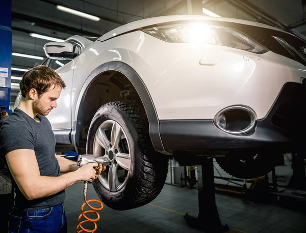 Meccanico che cambia ruota dell'automobile nel garage di riparazione auto — Foto Stock