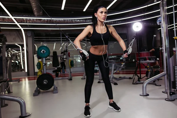 Femme en forme exécuter l'exercice avec la machine d'exercice Cable Crossover dans la salle de gym — Photo