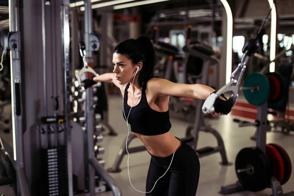 Jimnastik salonunda egzersiz makinesi kablolu yayınıyla egzersiz yapmaya hazır kadın. — Stok fotoğraf