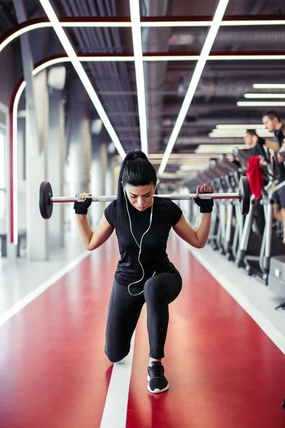 Meisje doet lunges met lange halter in moderne sportschool — Stockfoto