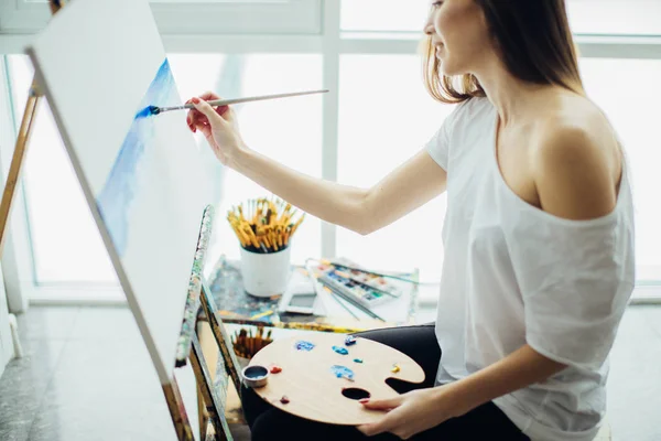 Kobieta artysta malarstwo obraz w dobrze oświetlonym studio — Zdjęcie stockowe