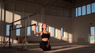 Yerde oturan yetenekli bir jimnastikçi.