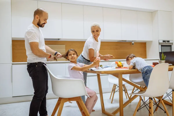 Happy young parents with children in kitchen — Stock Photo, Image