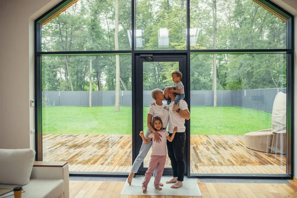 Wife with her husband and two chindren stand and look at big panoramic window — Stock Photo, Image