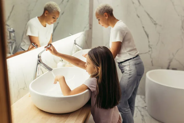 Kid girl and mother washing faces in bathroom — Stock Photo, Image