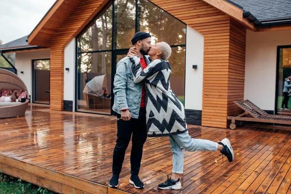 Casa, amor e conceito de férias. feliz casal stand beijos no fundo da casa de madeira — Fotografia de Stock