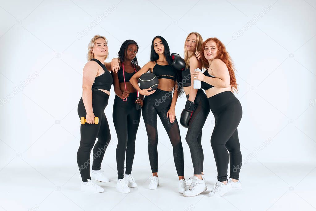 Portrait of five smiling multiethnic women wearing black sport clothes