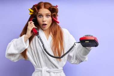 Ev telefonu olan bornozlu çekici bir kadın.