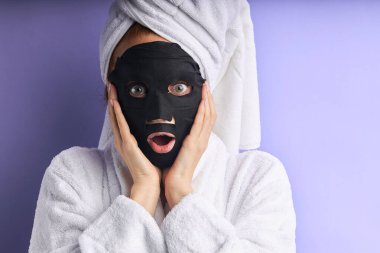 Yüz bakımı. Güzel beyaz kadın yüzü için siyah maske kullanıyor.