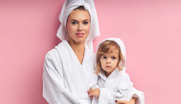 Atractiva madre y hermosa hija pequeña en toalla mira a la cámara — Foto de Stock