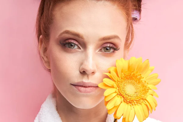 Foto de cerca de la hermosa cara natural de la mujer pelirroja sosteniendo la flor amarilla margarita — Foto de Stock