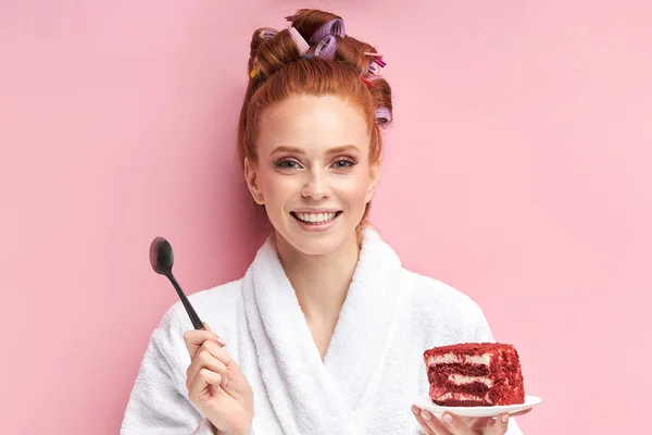 Hermosa joven comer sabroso pastel sobre fondo rosa — Foto de Stock