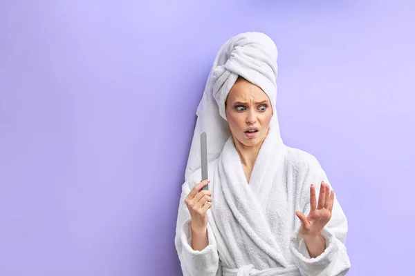 Mira con horror en las uñas. Mujer en albornoz, toallas mientras corta clavos — Foto de Stock